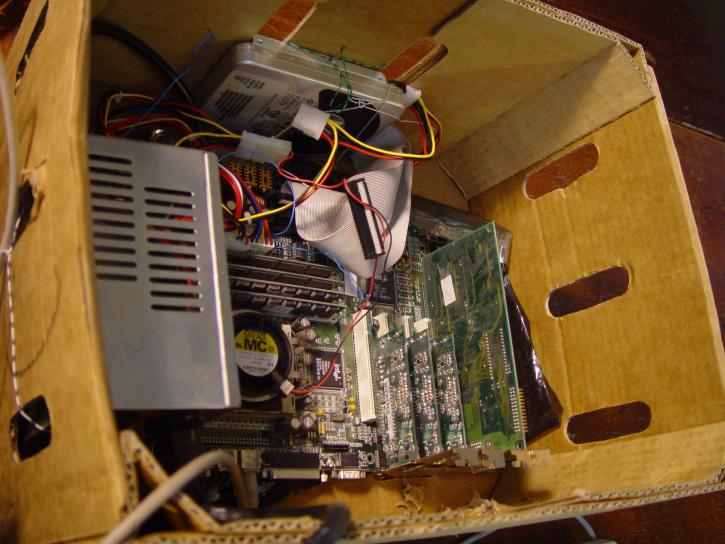 Computer components haphazardly placed into a box, but connected so that they create a functional device.