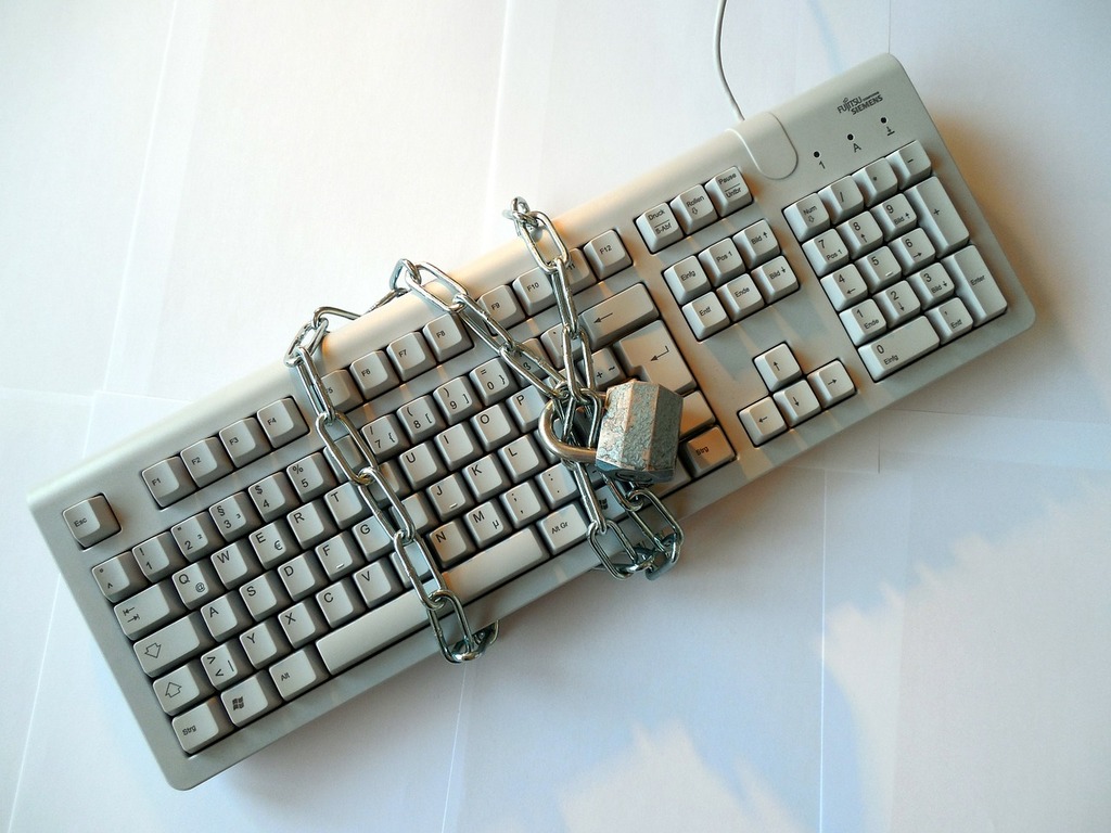 A Keyboard with a locked chain wrapped around it.